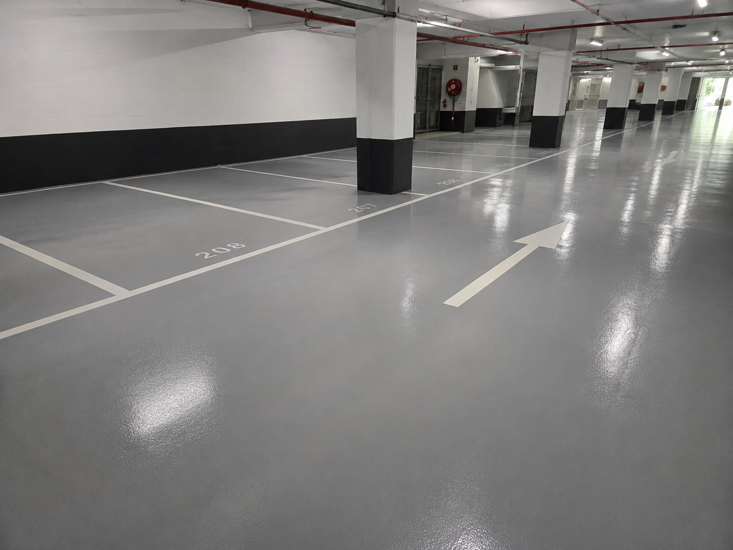 Polished and sealed basement carpark slab with mirror-like sheen and crisp white parking bay lines.